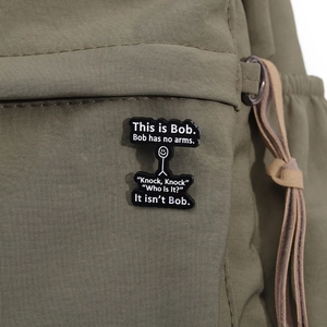 Funny This is Bob white stickman enamel pin on a green canvas backpack fabric