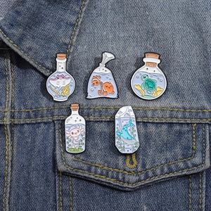 Set of 5 cartoon ocean animal enamel pins pinned on a blue denim jacket pocket