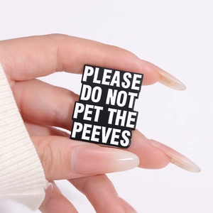 Detailed shot of a rectangular enamel pin with white text Please Do Not Pet The Peeves