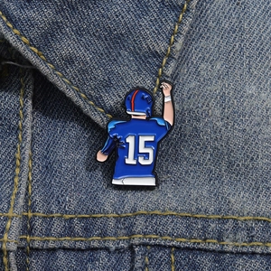 Detail of blue enamel football player pin featuring number 15 on denim fabric