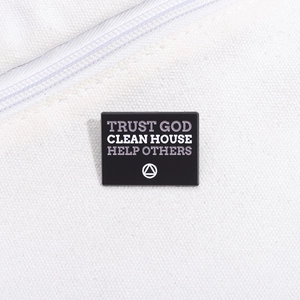 Détail macro du pin's Trust God Clean House sur un sac en toile blanche