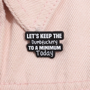 Détail macro du pin's émaillé avec citation humoristique sur tissu denim rose