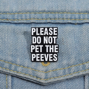 Funny enamel pin with 'PLEASE DO NOT PET THE PEEVES' text on denim jacket