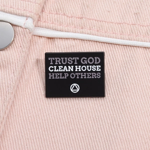 Gros plan sur le pin's en émail noir avec citation sur une veste en jean rose