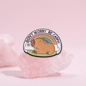 Cute capybara enamel pin with rainbow and Don't Worry Be Cappy text on pink crystal base