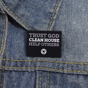 Gros plan d'un pin's en émail noir avec texte motivant sur du tissu en denim bleu