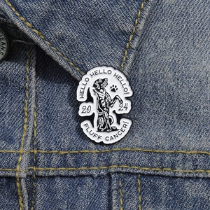 Gros plan d'une broche chien en émail avec texte 'FLUFF CANCER' sur veste en jean