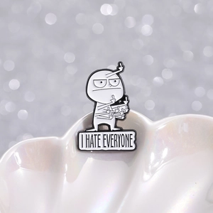 Minimalist enamel pin featuring a cartoon figure and I HATE EVERYONE text on a shell