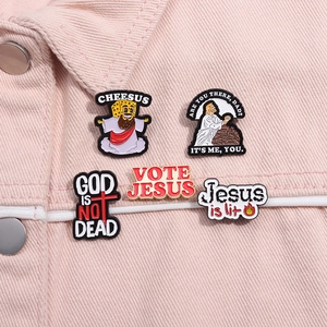 Close-up of five colorful enamel pins with religious humor on a pink denim jacket
