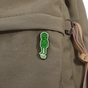 Detail of Picolas Cage enamel pin with funny cucumber design on green canvas bag