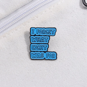 Pin's émaillé bleu avec citation 'I FORGET WHAT EIGHT WAS FOR' sur toile de fond blanche
