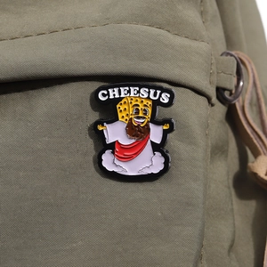 Detailed view of a funny Cheesus enamel pin attached to a green canvas backpack