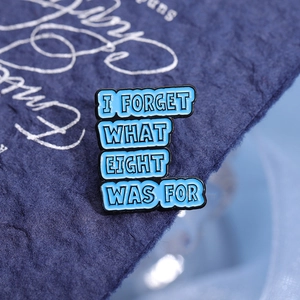 Insigne métallique bleu avec texte anglais I FORGET WHAT EIGHT WAS FOR sur fond tissu