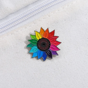 Détail de la broche tournesol arc-en-ciel épinglée sur une toile blanche