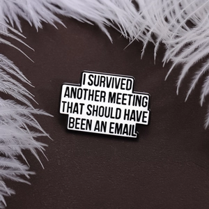 Funny office humor enamel pin with I Survived Another Meeting text on a white feather