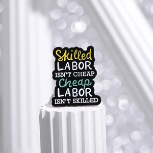 Minimalistische Emaille-Brosche mit 'Skilled Labor'-Zitat auf weißer Säule
