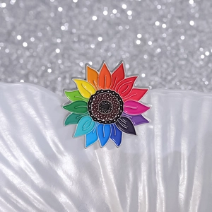Broche tournesol arc-en-ciel en émail aux pétales colorés sur un support coquillage