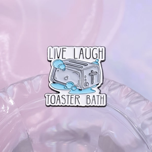 Funny blue toaster enamel pin featuring Live Laugh Toaster Bath text on glass