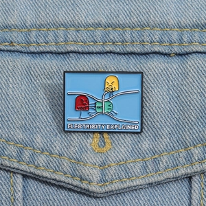 Cartoon electricity explained enamel pin with Volt Amp Ohm characters on denim jacket
