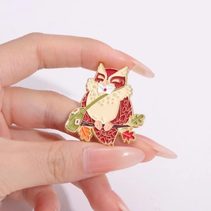Détail d'une broche hibou avec feuilles d'érable et enveloppe sur socle doré
