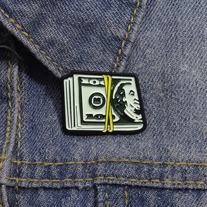 Détail macro d'un pin's émaillé billet de 100 dollars sur un col en jean bleu