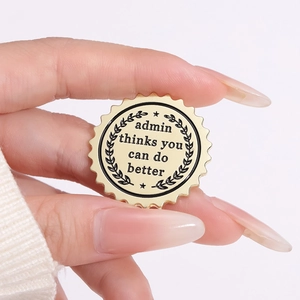 Close-up of golden enamel brooch with black engraved 'admin thinks you can do better' text