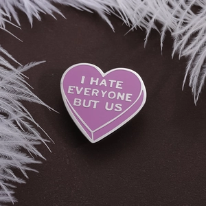 Spilla cuore in smalto viola con scritta I Hate Everyone But Us su fondo rustico