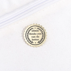 Detail of round gold enamel pin with engraved motivational message on canvas