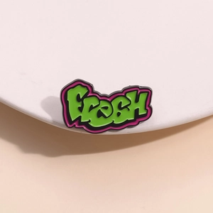 Detailed close-up of a green graffiti-style enamel pin featuring the word FRESH