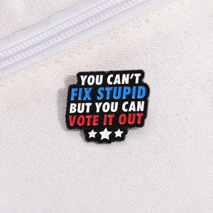 Detail of metal enamel pin with slogan YOU CAN'T FIX STUPID BUT YOU CAN VOTE IT OUT
