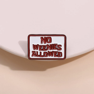 Detail of square enamel pin with No Weenies Allowed text on a soft pink pedestal