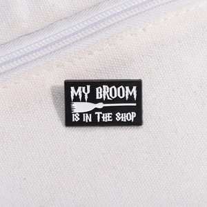Detail of My Broom Is In The Shop enamel pin with white lettering on black background