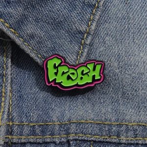 Künstlerische FRESH Emaille-Anstecknadel in Grün und Rosa auf einer Jeansjacke