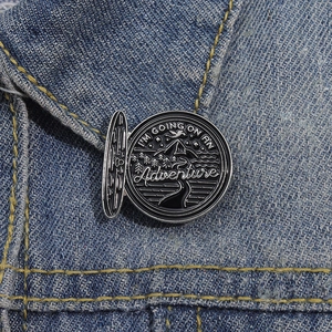 Détail de l'épinglette d'aventure avec montagnes sur une veste en jean bleu clair