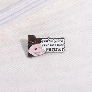 Detailed view of an enamel possum brooch wearing a cowboy hat on a white canvas background