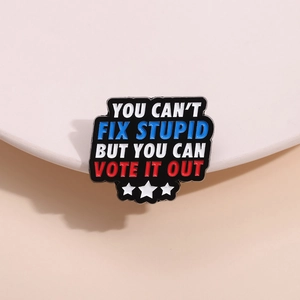 Macro detail of enamel brooch with 'YOU CAN'T FIX STUPID' text and star decorations