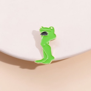 Detail of green long-legged frog enamel brooch with gold trim and black bow tie