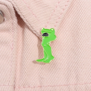 Funny green frog enamel pin with sunglasses and long legs on pink denim fabric