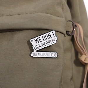 Detail of WE DON'T LICK PEOPLE enamel pin on olive green canvas backpack