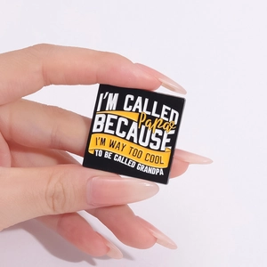 Black square Papa enamel pin with funny text held by hand on a white background