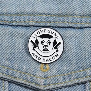 Funny pig badge with I Love Guns And Bacon text pinned on blue denim fabric background