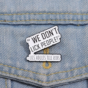 Funny enamel badge with 'We don't lick people' text pinned on a blue denim jacket