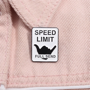 Détail de l'épingle émaillée Speed Limit avec signe shaka sur une veste en jean rose