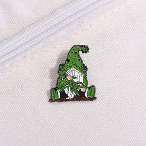 Détail macro du pin's émaillé gnome avec chapeau vert et motif feuille de cannabis