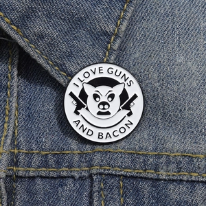Dettaglio della spilla smaltata Guns and Bacon su tessuto denim con scritte bianche