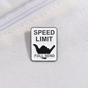Macro shot of Speed Limit Full Send enamel pin with Shaka hand sign on white canvas