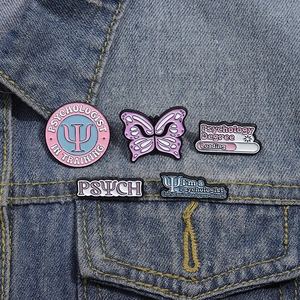 Five-piece set of psychology-themed enamel pins pinned on a blue denim jacket pocket
