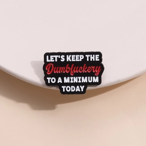 Minimalistische Emaille-Brosche mit schwarzem Hintergrund und markantem Slogan-Schriftzug