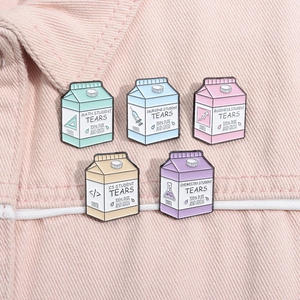 Detail view of five creative student-themed milk box enamel pins on pink denim fabric