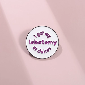 Minimalist round white enamel pin with purple text 'i got my lobotomy at claires'
